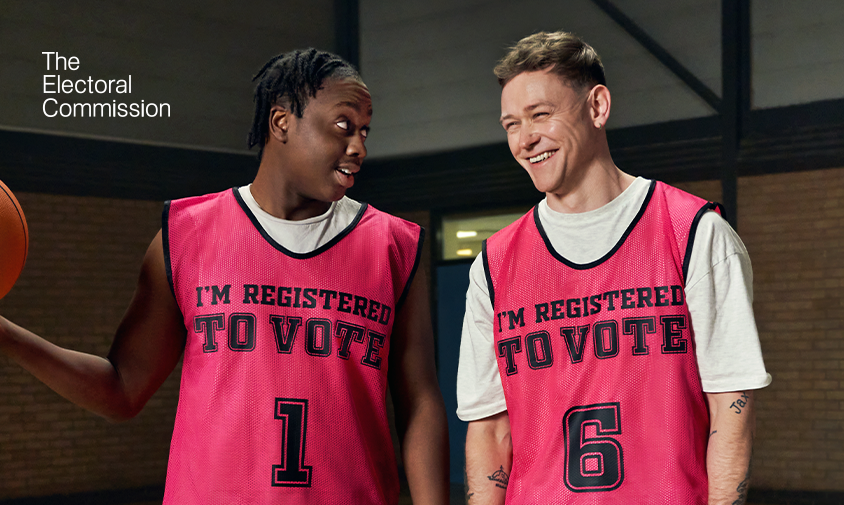 Two young men with pink vests on that say 'I'm registered to vote'