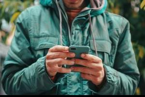 A person in a coat holding a phone and looking at the screen 