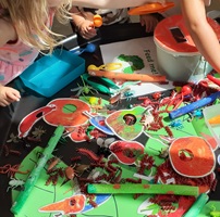 small children doing colourful insect crafts ona table