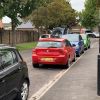 Line of clean and highliy polished vehicles parked along the kerbside of a residential street