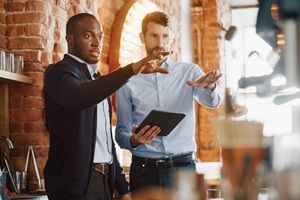 Two men pointing. One holds an iPad.