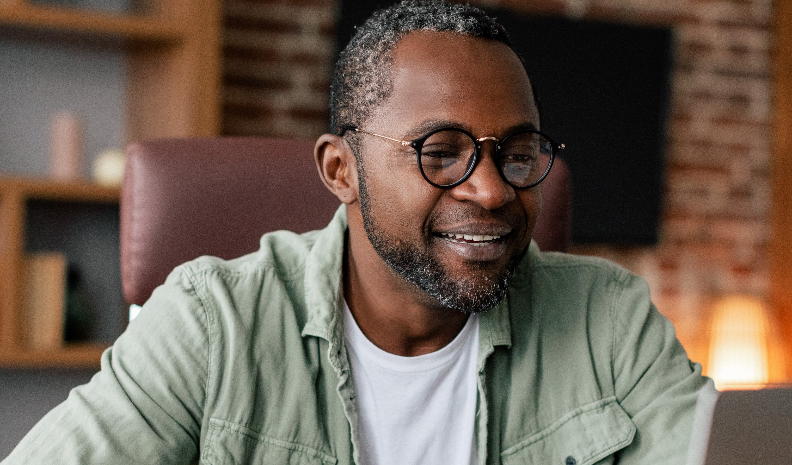 Man wearing glasses looking at a laptop.