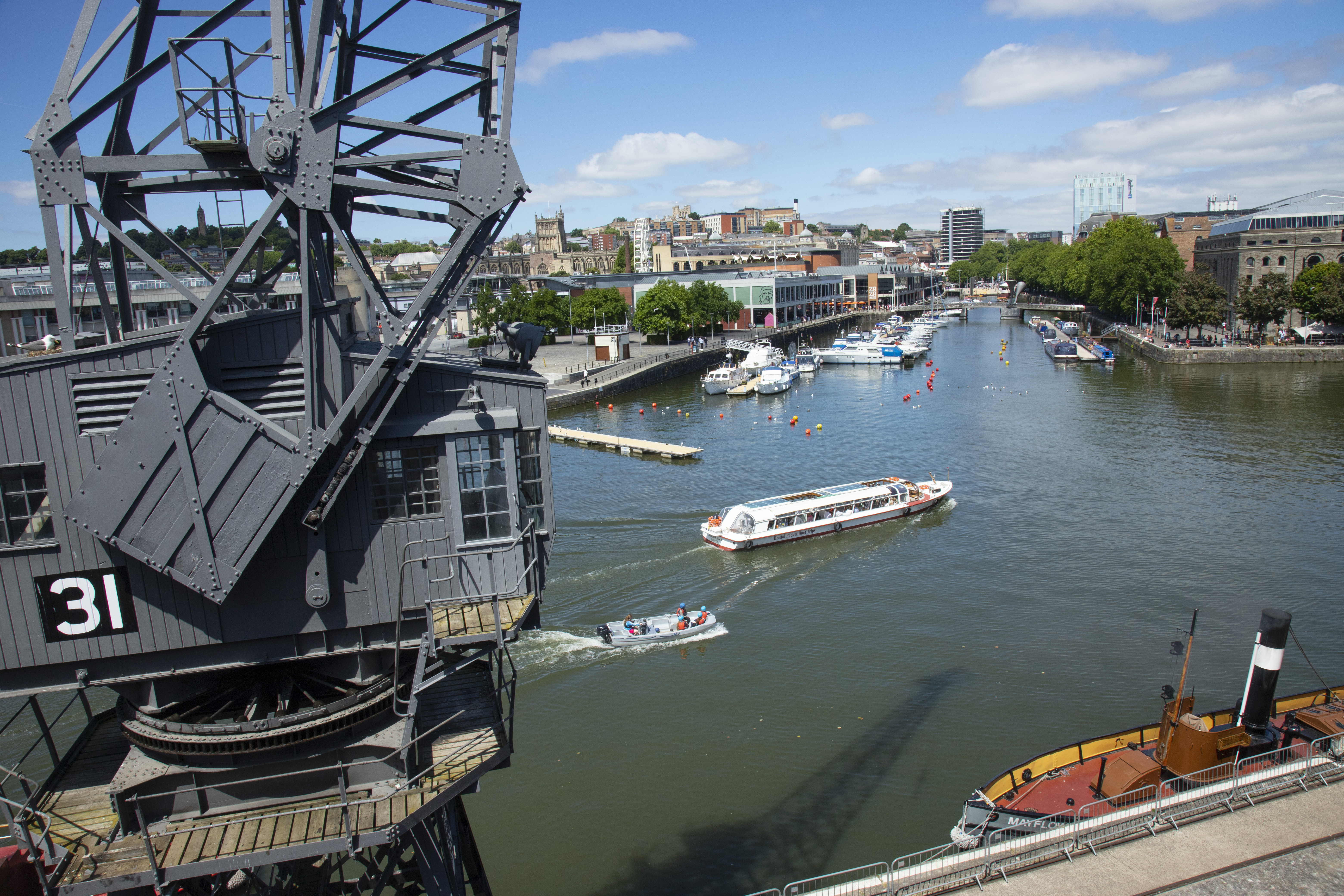 A crane at the harbour, the water in the background, boats on the water, a blue sky