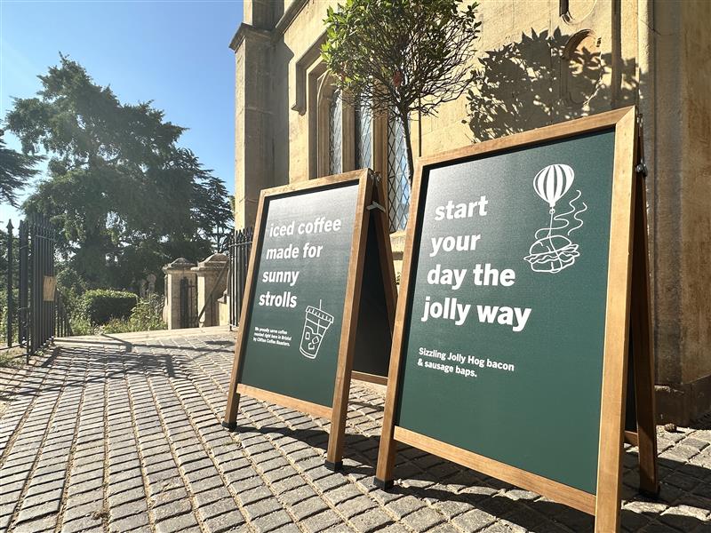 Two sandwich boards advertising coffee outside a cafe on a sunny day