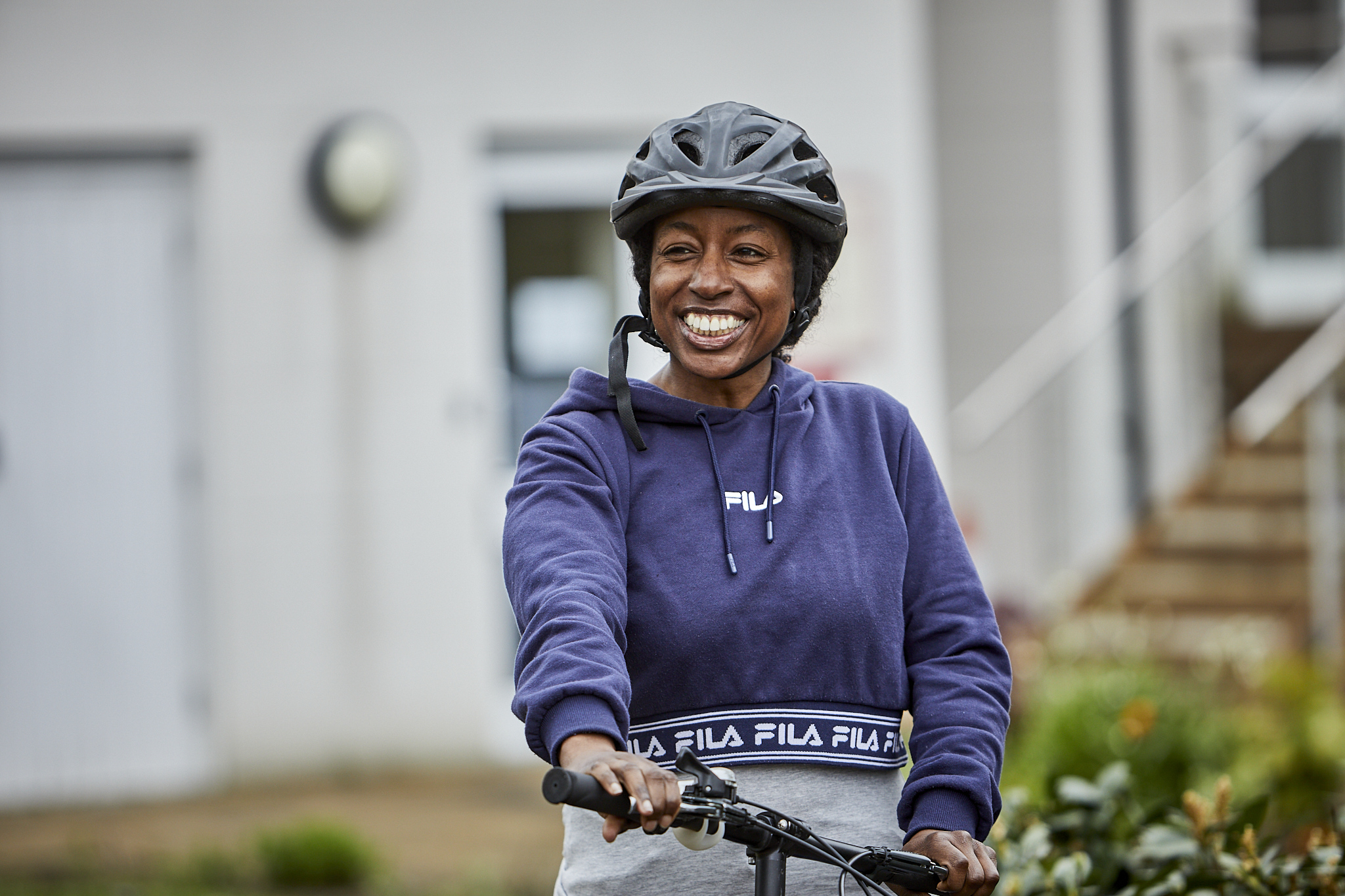A smiling lady wearing a cycle helmet on a bike