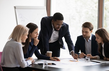 A group of people in a meeting looking at some work.