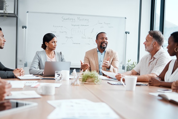 A group of people sat around a table engaged in a meeting.