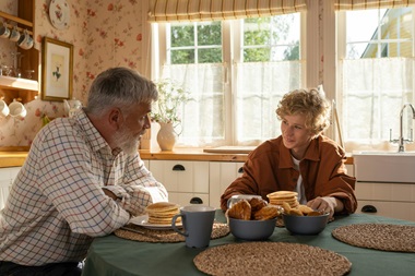 A father and son having a conversation at the dining room table.