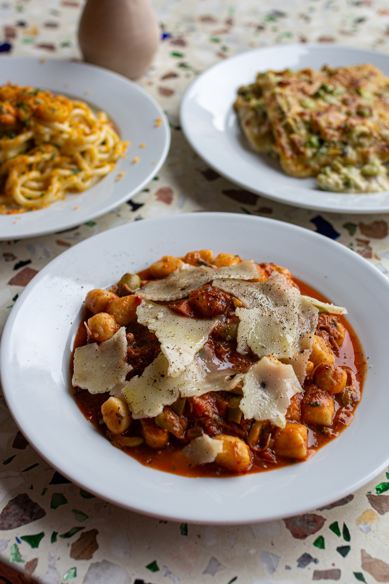 A close up of a bowl gnocchi pasta in a rich tomato sauce with parmesan cheese grated on top