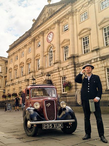 A man dressed as a Second world war warden stands by an Austin 7 car in front of the Corn Exchange building in Bristol