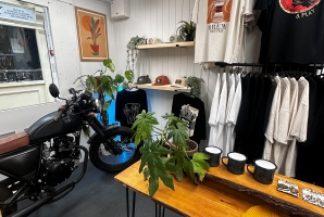 T shirts hanging on a wall behind a table with plants on 
