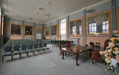 A large room with large paintings on the wall and several rows of chairs