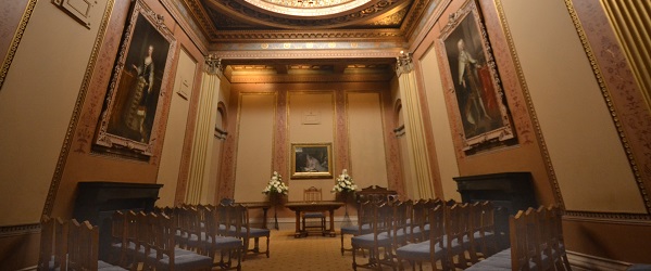 a high ceilinged room with paintings on the walls